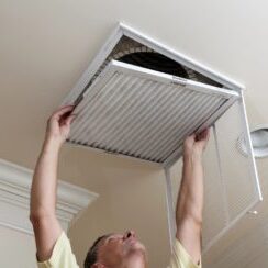 Technician replacing a ceiling air filter during a tune-up